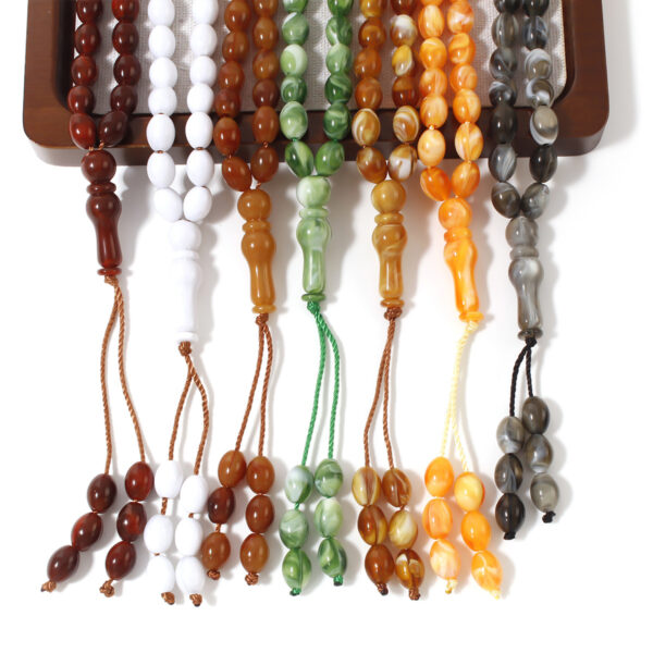 Mano sosteniendo un Tasbih de color vibrante del pack de 7, con fondo desenfocado